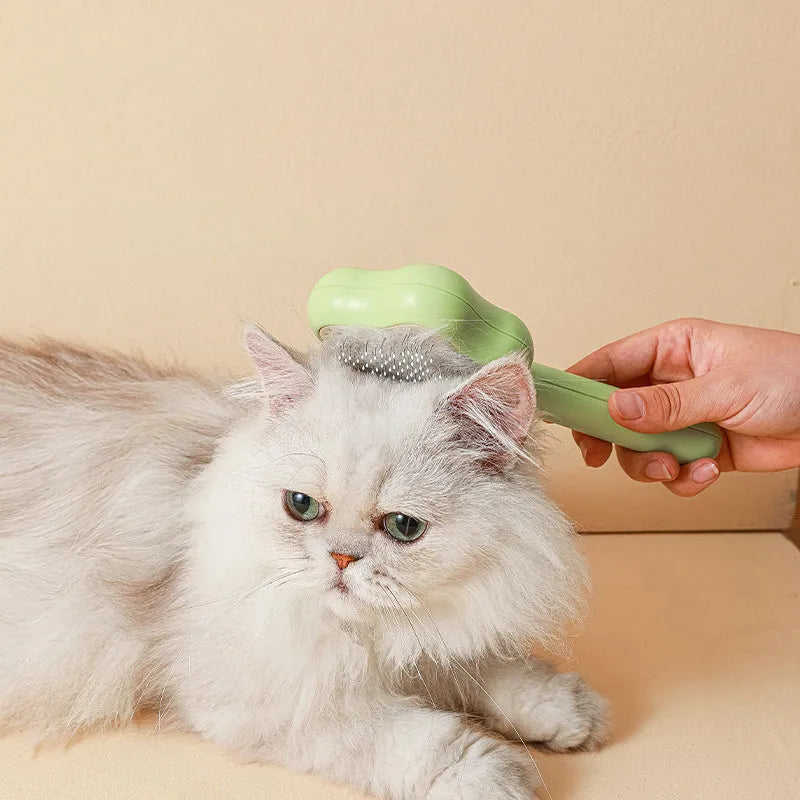 Green stainless steel cat comb with magic wand self-cleaning mechanism showing needle teeth and plastic handle