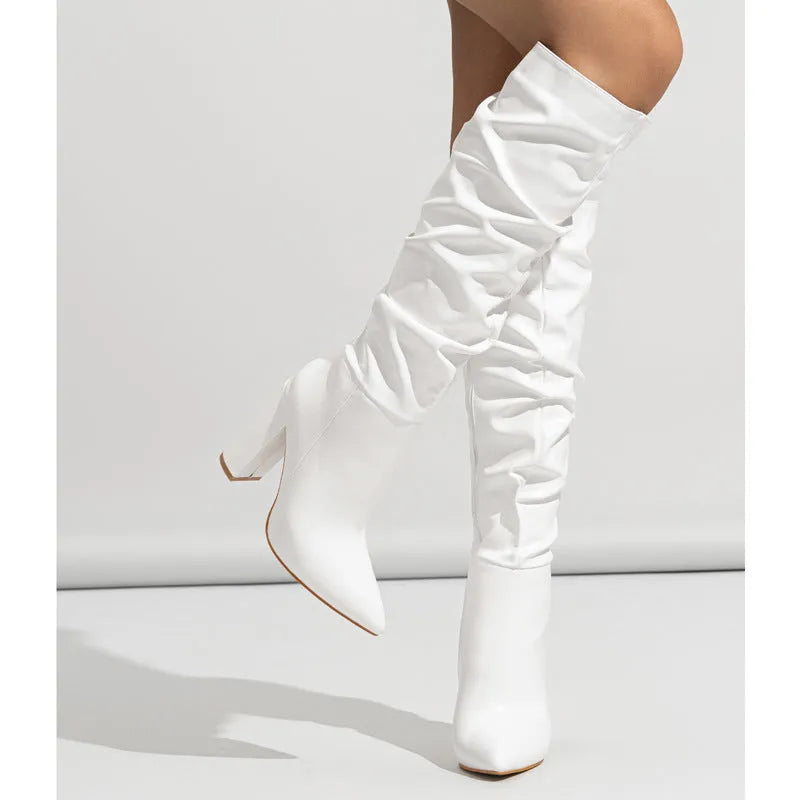 Women's white pointed toe high-heel ankle boots with side zipper on a pink background.