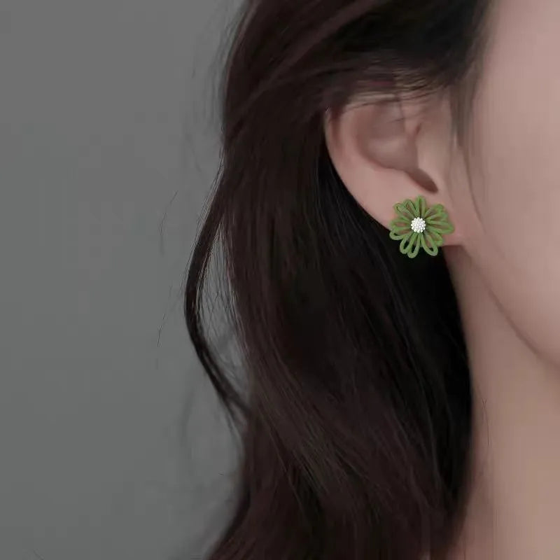 Close-up of cartoon-style flower stud earrings in alloy, shown in blue and orange two-tone colour combination.
