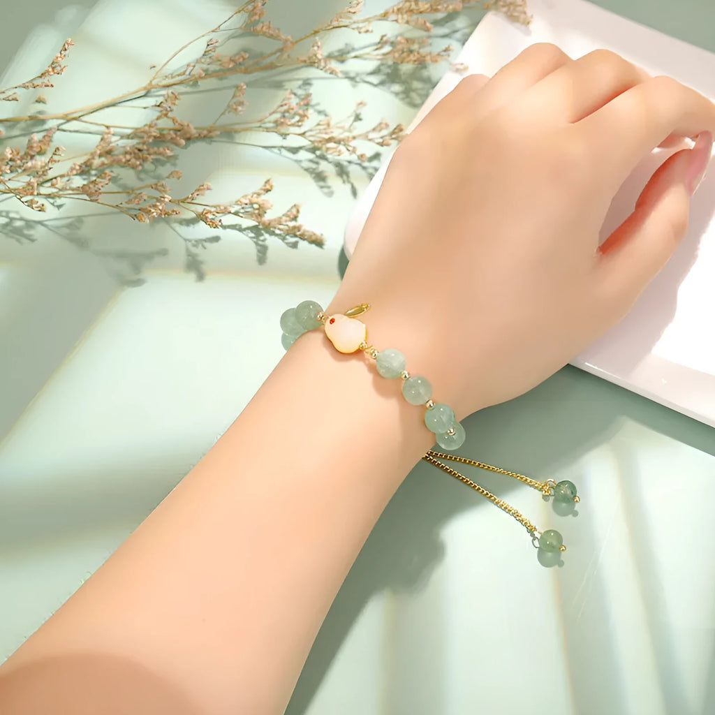 Green aventurine and strawberry quartz rabbit charm bracelet on a copper and gold chain.