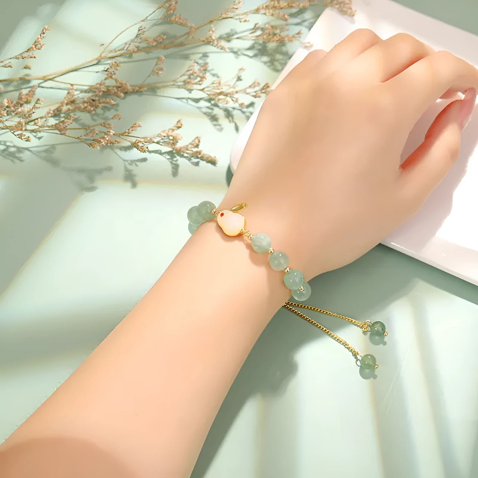 Green aventurine and strawberry quartz rabbit charm bracelet on a copper and gold chain.