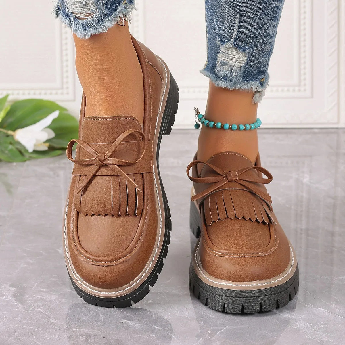 Plus size women's black loafers with a decorative bowknot and tassel on a chunky rubber sole.