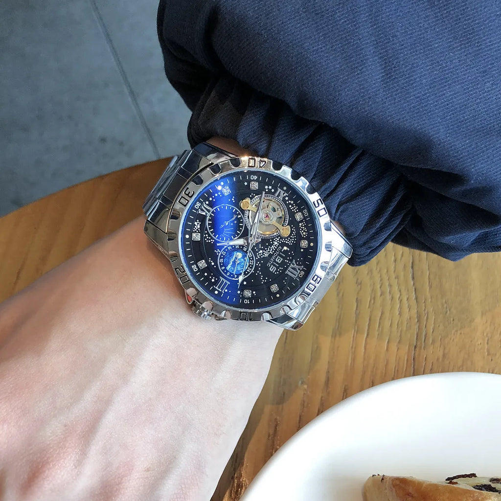 Men's silver automatic watch with black starry dial, luminous hands, and brown leather strap