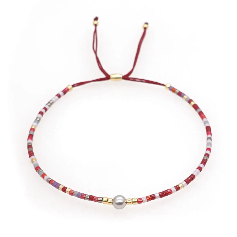 Handmade bohemian bracelet with colourful glass and glaze geometric beads on a wrist.