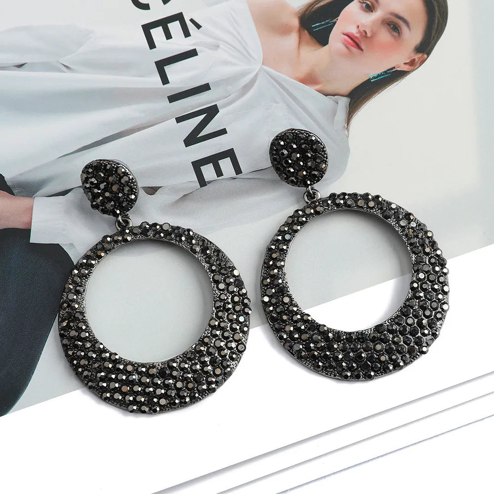 A pair of large, round, colour diamond-shaped cartoon-style metal pendant earrings on a white background.
