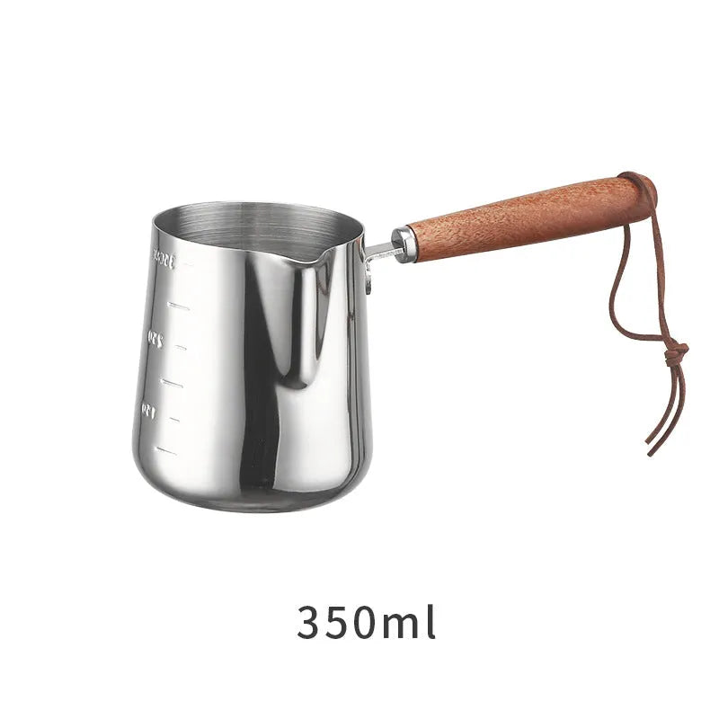 Stainless steel milk pouring cup with wooden handle and interior volume measurement scale.