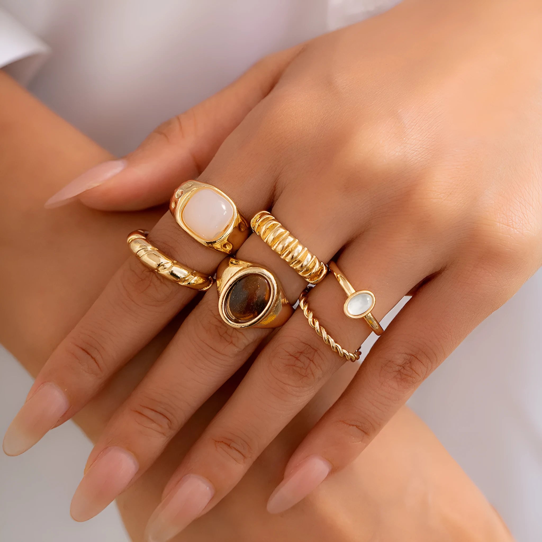 Six light gold alloy rings with geometric shapes and round elements arranged as a jewellery set