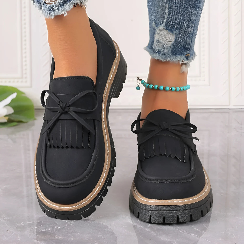 Plus size women's black loafers with a decorative bowknot and tassel on a chunky rubber sole.