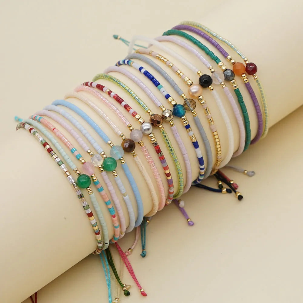 Handmade bohemian bracelet with colourful glass and glaze geometric beads on a wrist.