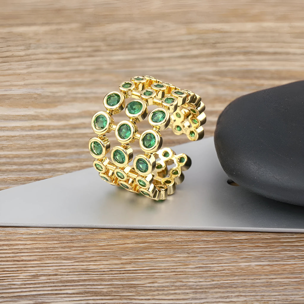 Gold plated ring with three-layer design and green zircon stones on a wide band.
