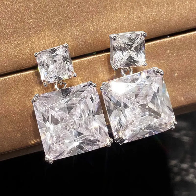 A pair of geometric square earrings in gold and white gold plating options, shown from the front.