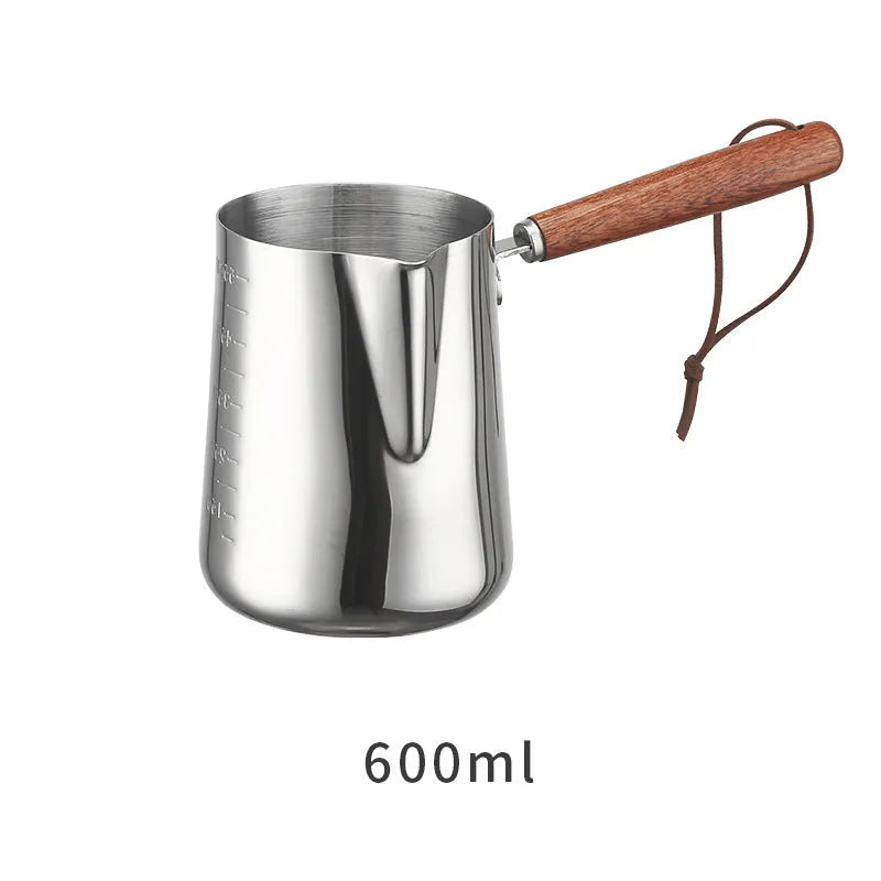 Stainless steel milk pouring cup with wooden handle and interior volume measurement scale.
