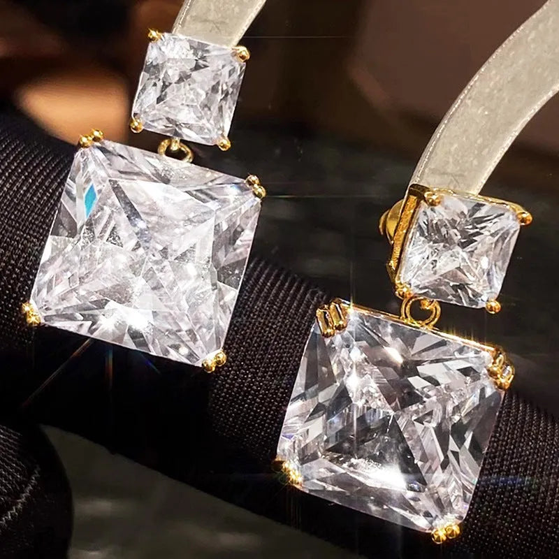 A pair of geometric square earrings in gold and white gold plating options, shown from the front.