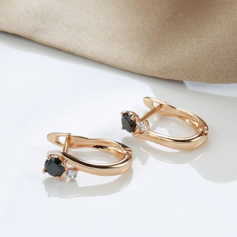 Gold geometric drop earrings with artificial gemstone inlay on black background
