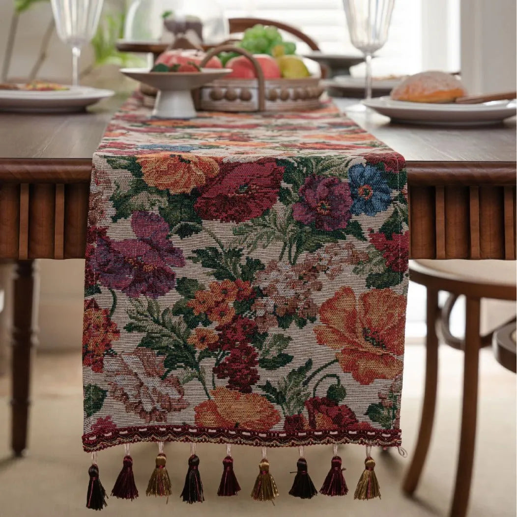 Beige jacquard table runner with long tassels and floral pattern laid on a wooden table