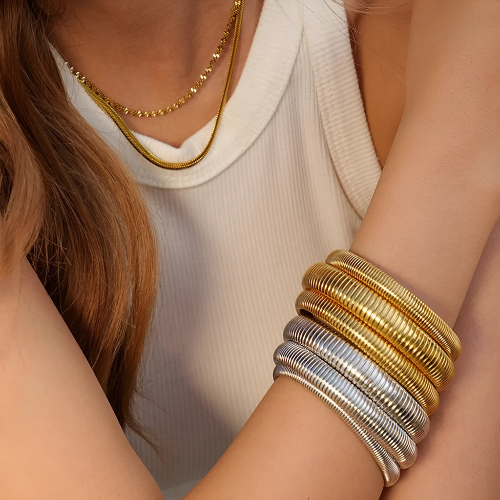 Women's gold titanium steel elastic bracelet with vertical stripe ring pattern, shown at an angle.