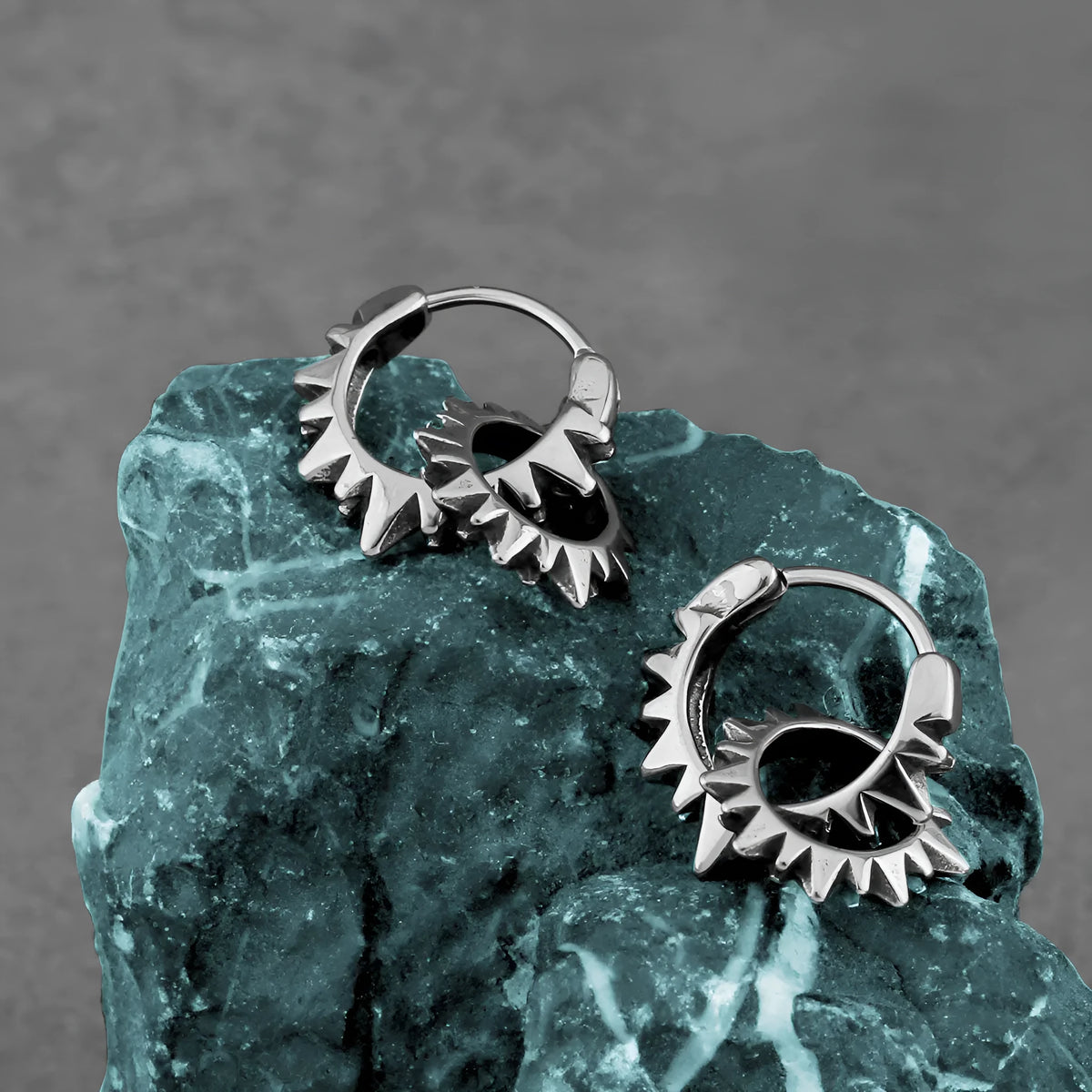 A pair of polished stainless steel round ring earrings with a titanium steel plating in a steel colour.