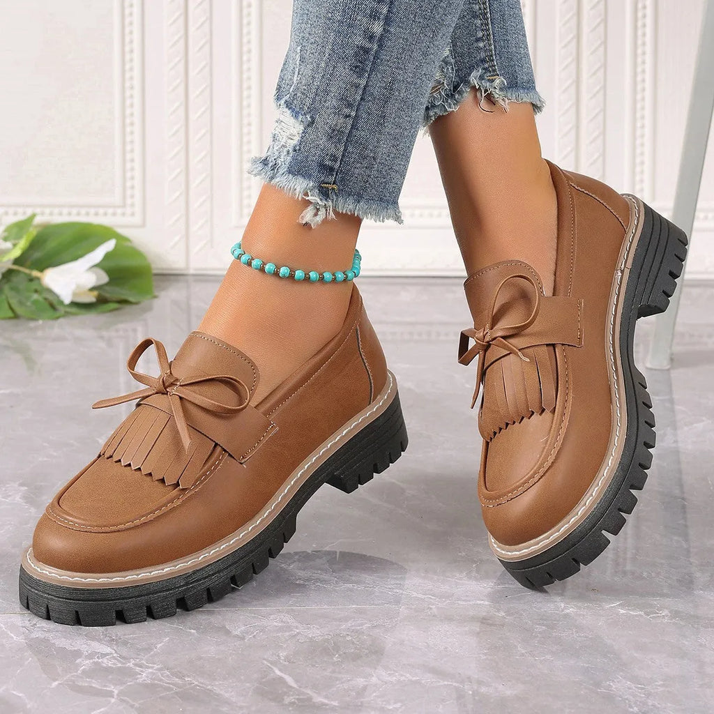 Plus size women's black loafers with a decorative bowknot and tassel on a chunky rubber sole.
