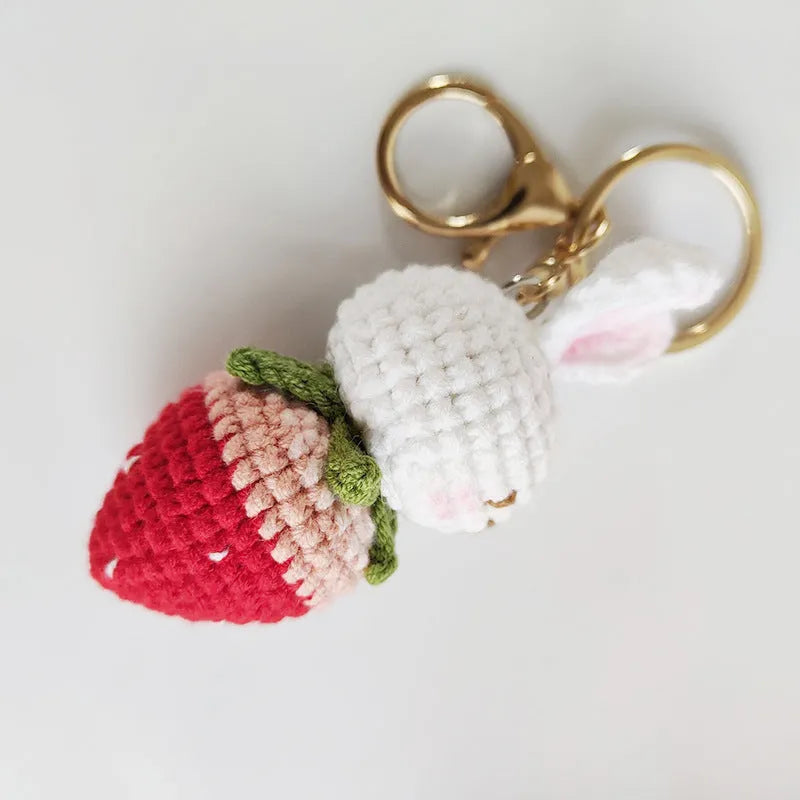 Hand-woven white wire pendant keyring with cartoon rabbit and strawberry design.