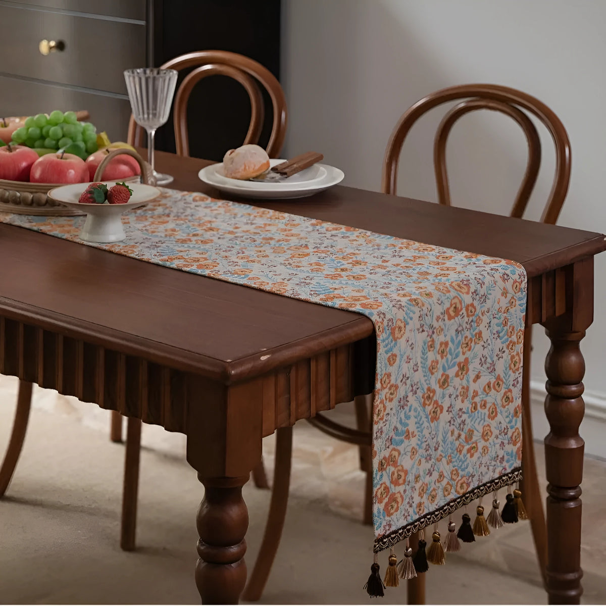 Beige jacquard table runner with long tassels and floral pattern laid on a wooden table