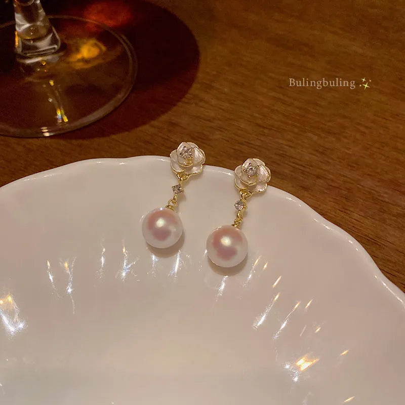 Close-up of a pair of camellia flower stud earrings for women in alloy metal.