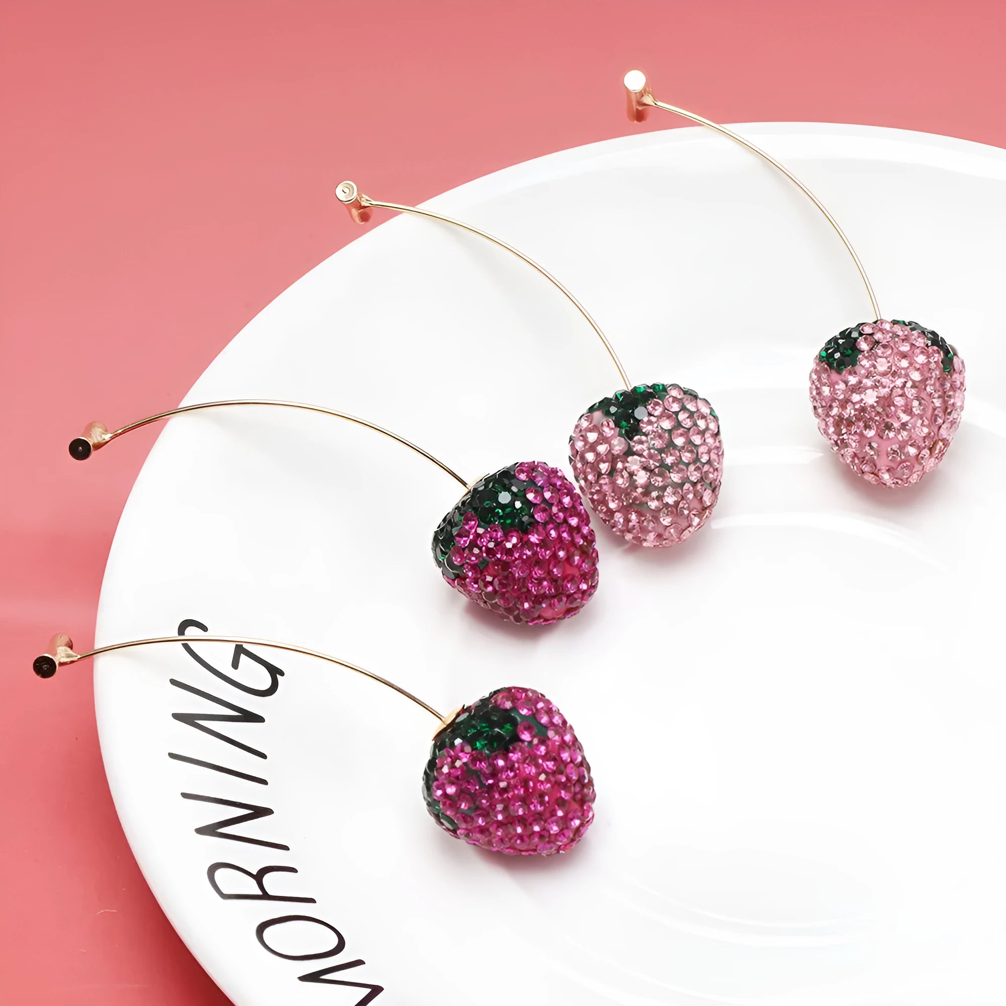 Close-up of geometric spot-drill strawberry stud earrings in red zinc alloy, shown on a plain background.