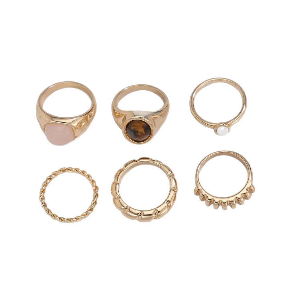 Six light gold alloy rings with geometric shapes and round elements arranged as a jewellery set