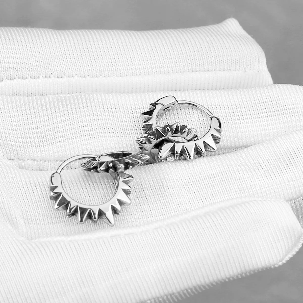 A pair of polished stainless steel round ring earrings with a titanium steel plating in a steel colour.
