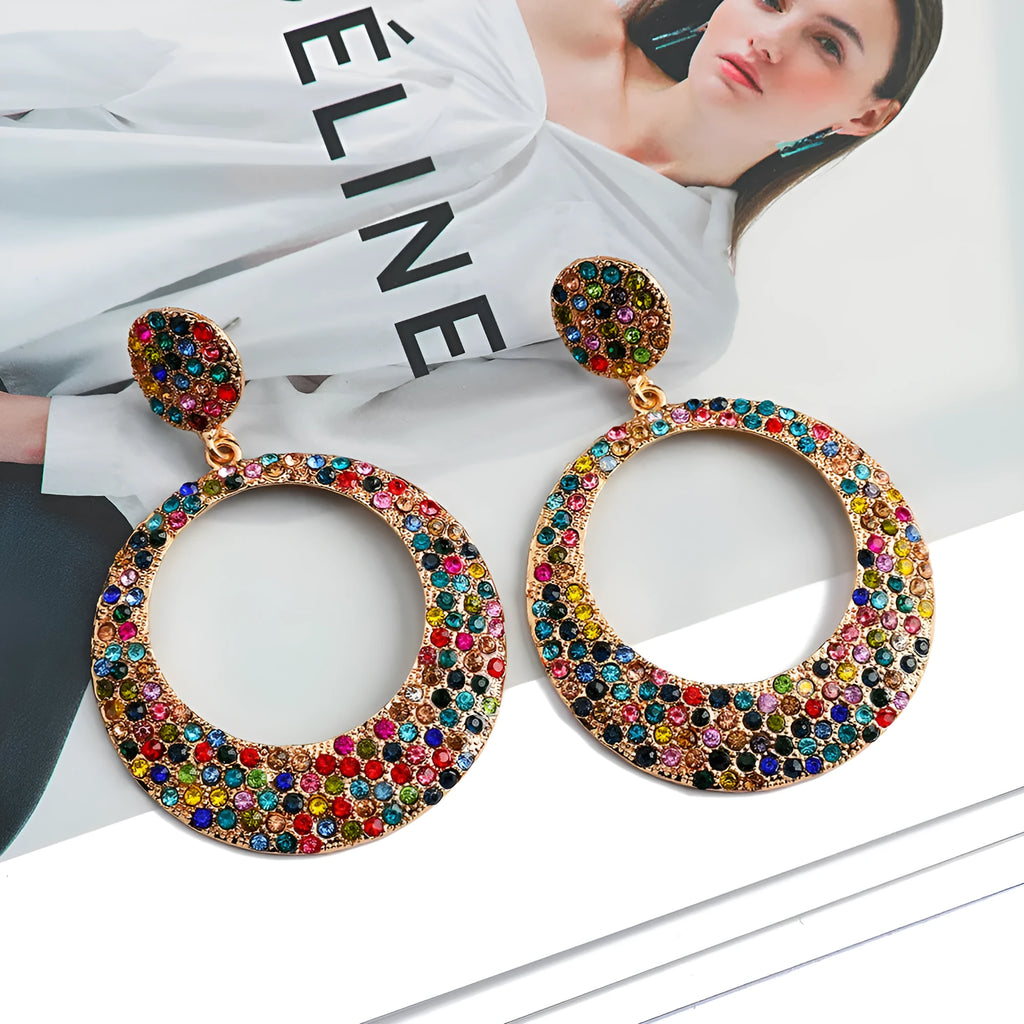 A pair of large, round, colour diamond-shaped cartoon-style metal pendant earrings on a white background.
