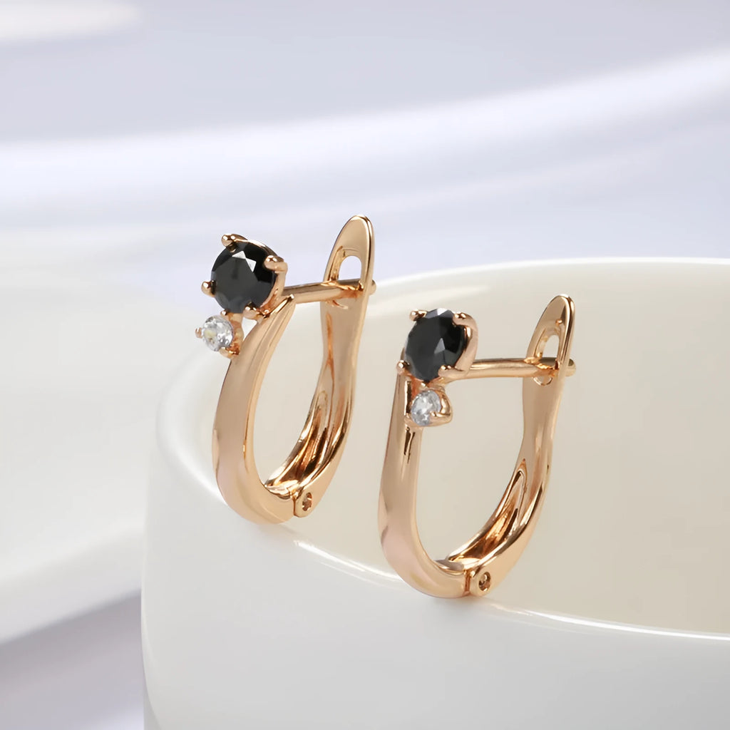 Gold geometric drop earrings with artificial gemstone inlay on black background