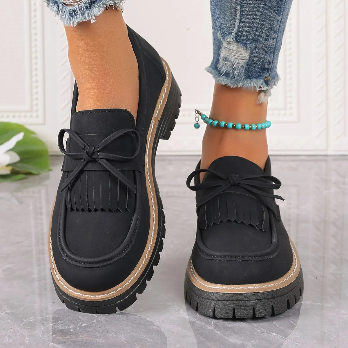 Plus size women's black loafers with a decorative bowknot and tassel on a chunky rubber sole.