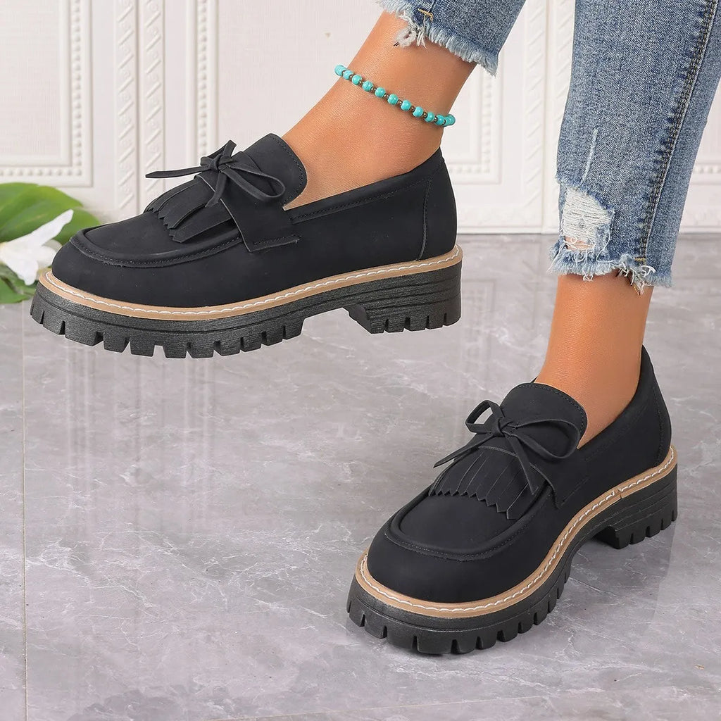 Plus size women's black loafers with a decorative bowknot and tassel on a chunky rubber sole.