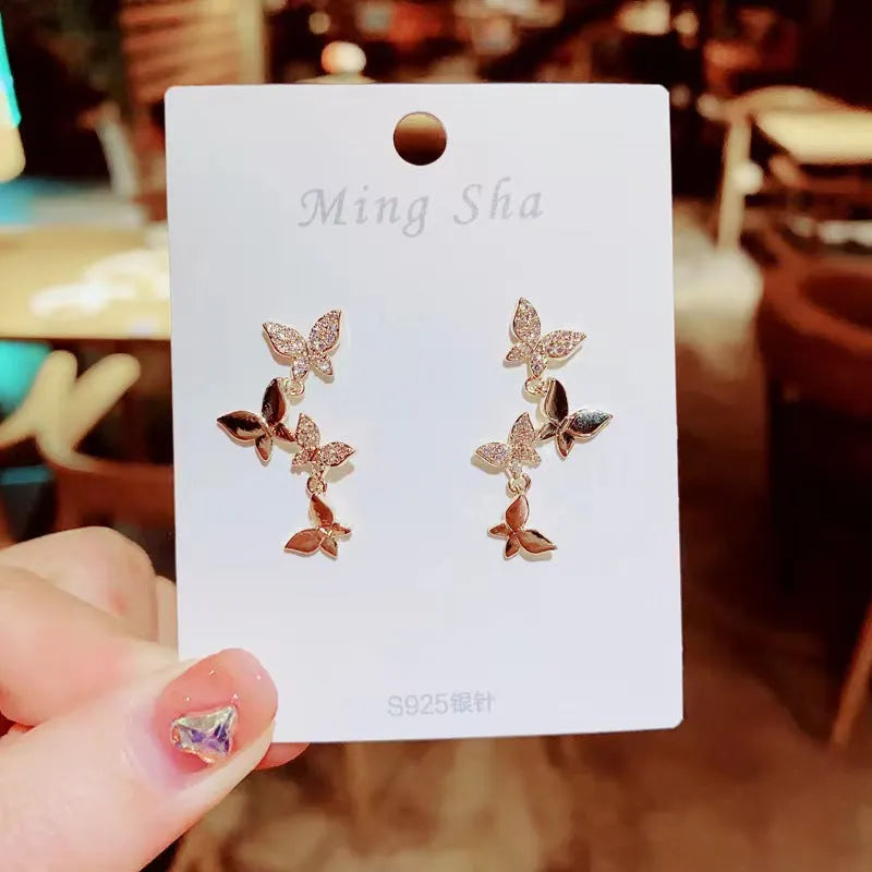 A pair of gold-coloured copper earrings with four detailed butterfly designs in a drop style.