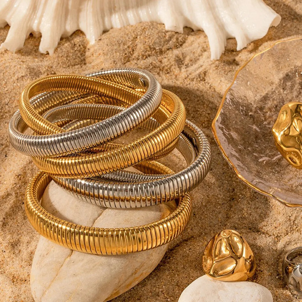 Women's gold titanium steel elastic bracelet with vertical stripe ring pattern, shown at an angle.