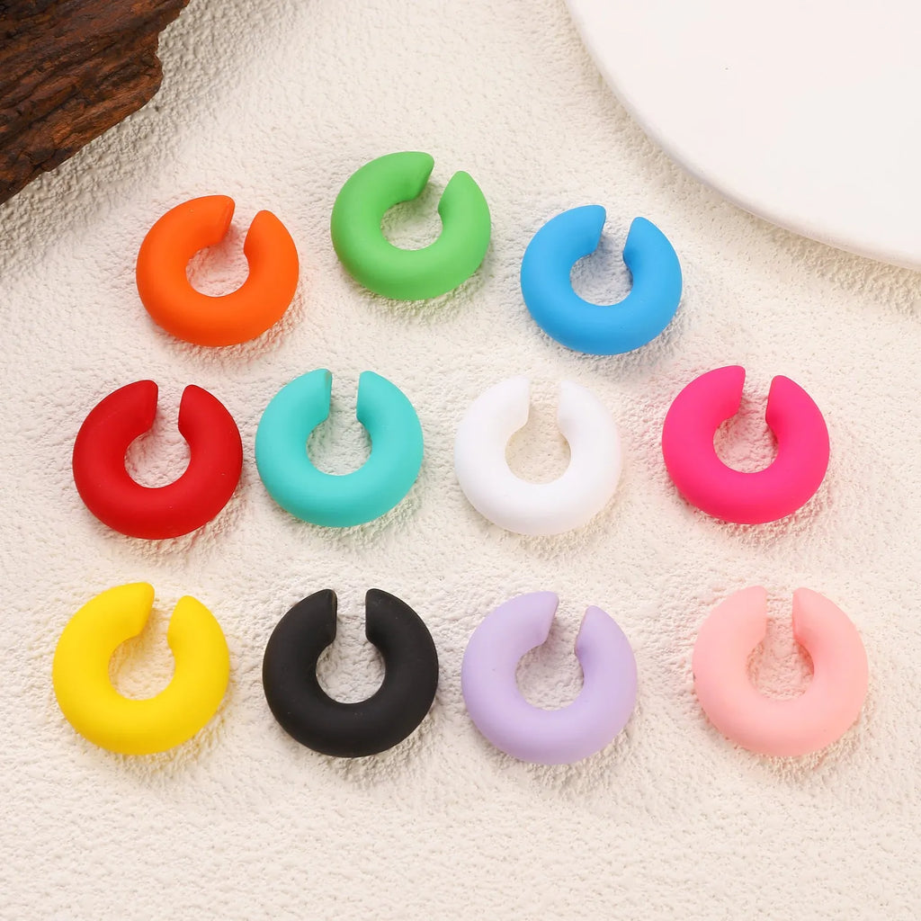 Geometric C-shaped matte clip-on earrings in multiple candy colours on a white background.