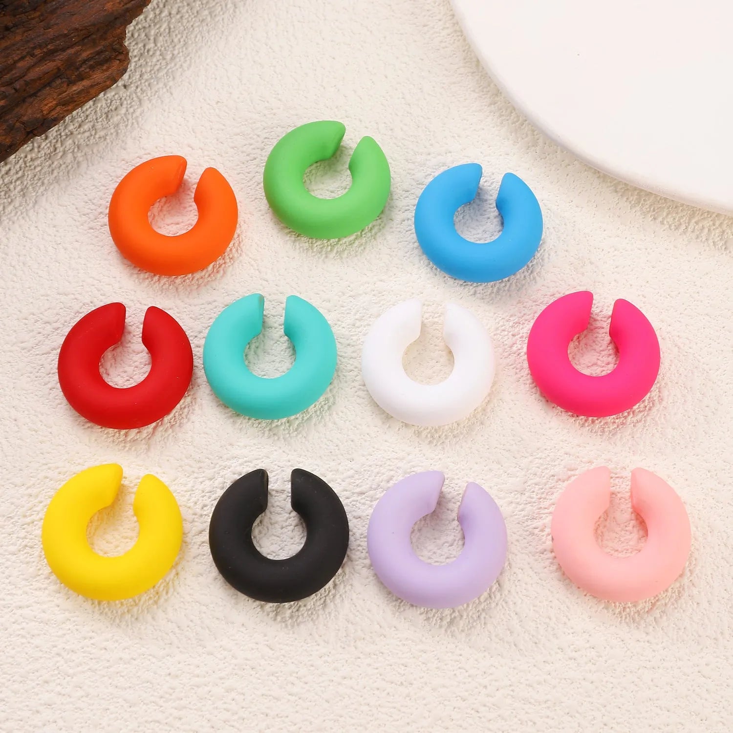 Geometric C-shaped matte clip-on earrings in multiple candy colours on a white background.