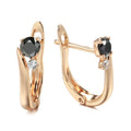 Gold geometric drop earrings with artificial gemstone inlay on black background