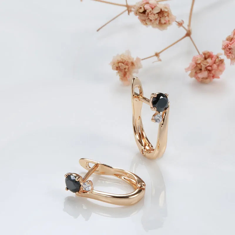 Gold geometric drop earrings with artificial gemstone inlay on black background