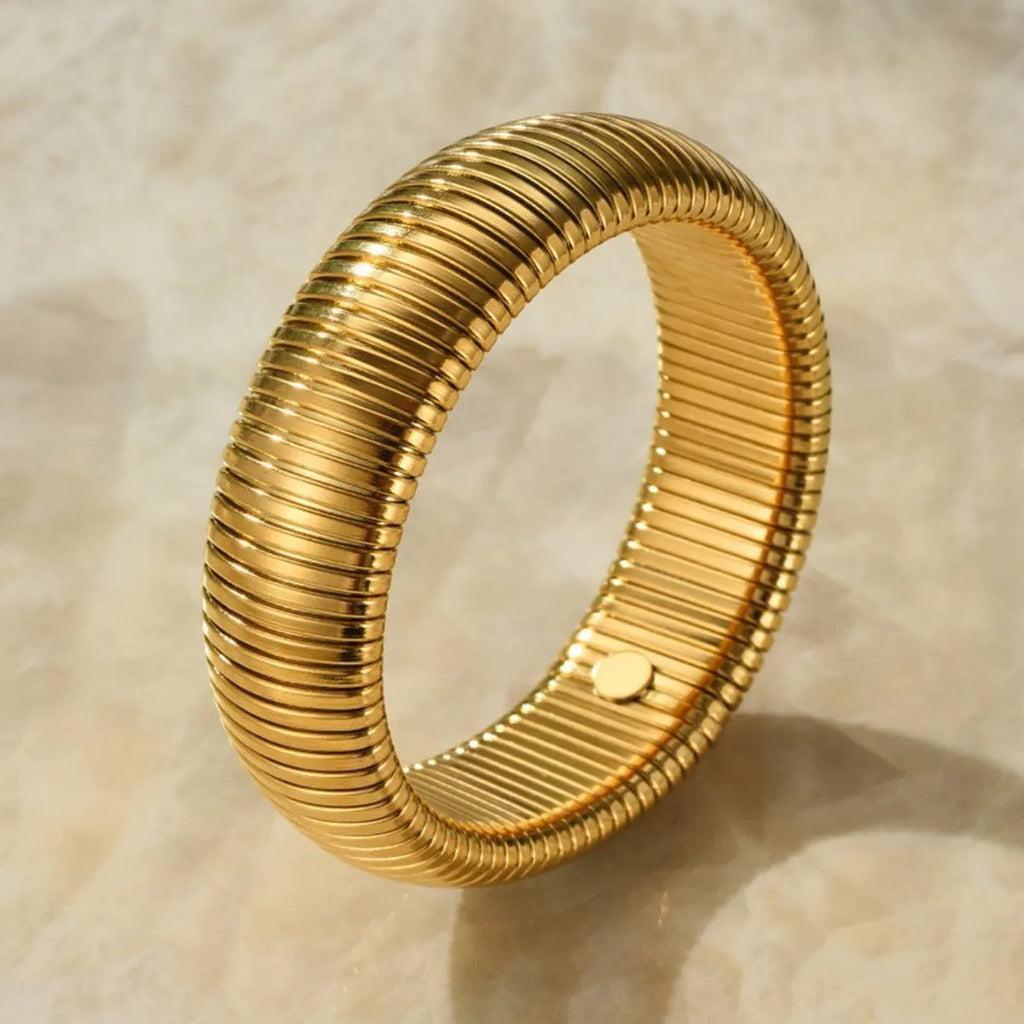 Women's gold titanium steel elastic bracelet with vertical stripe ring pattern, shown at an angle.