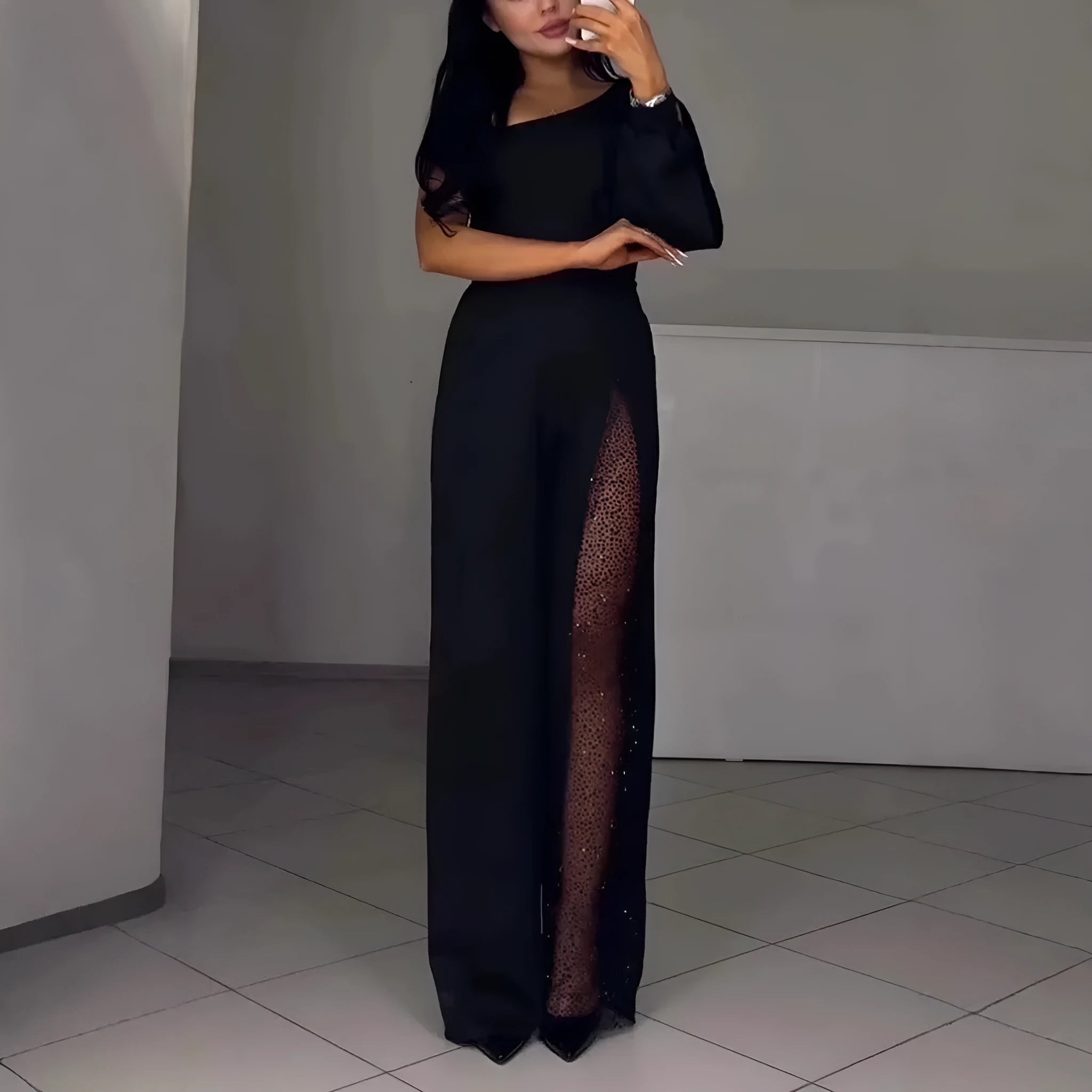 Black women's jumpsuit with an oblique off-shoulder neckline and a high slit on the leg.