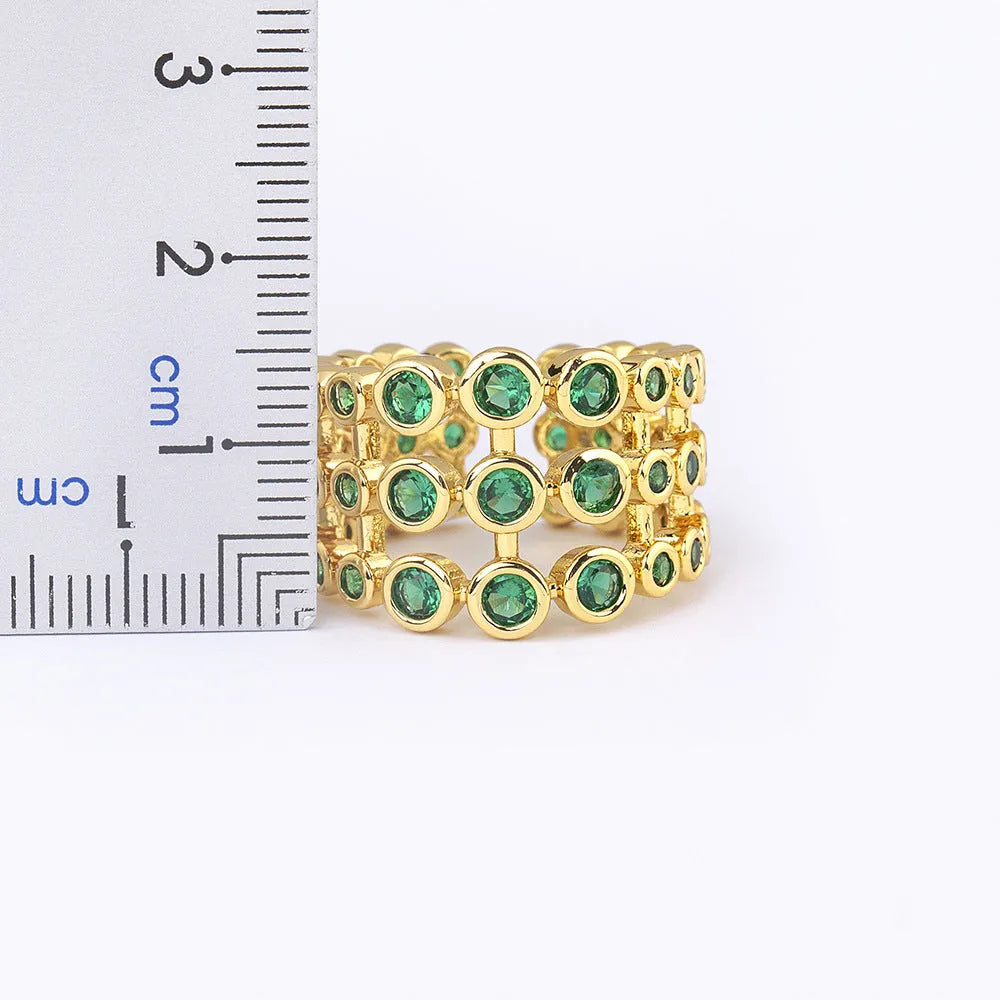 Gold plated ring with three-layer design and green zircon stones on a wide band.