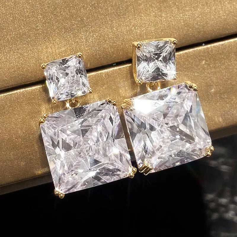 A pair of geometric square earrings in gold and white gold plating options, shown from the front.
