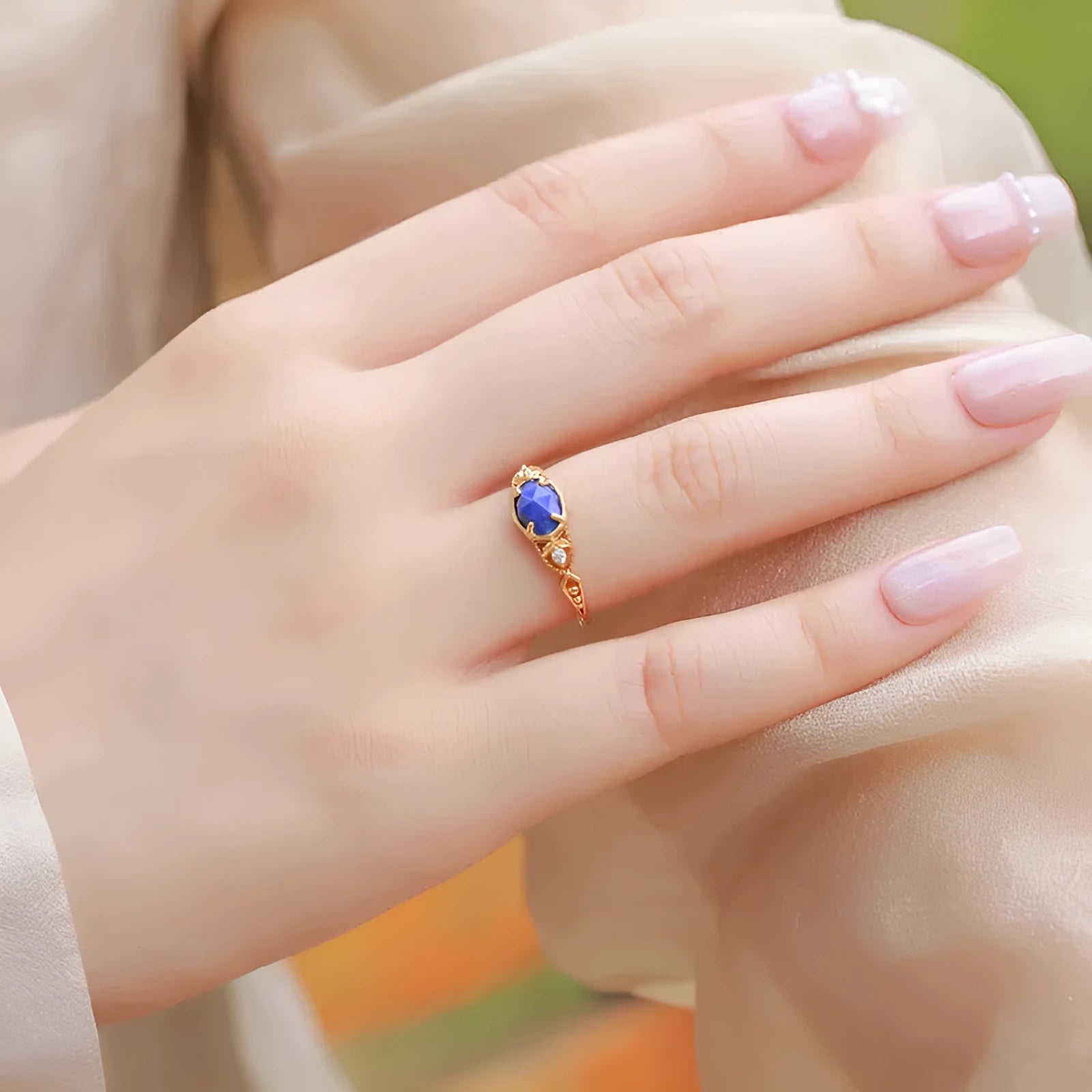 Silver geometric ring with an oval blue lapis lazuli stone on a model's finger.