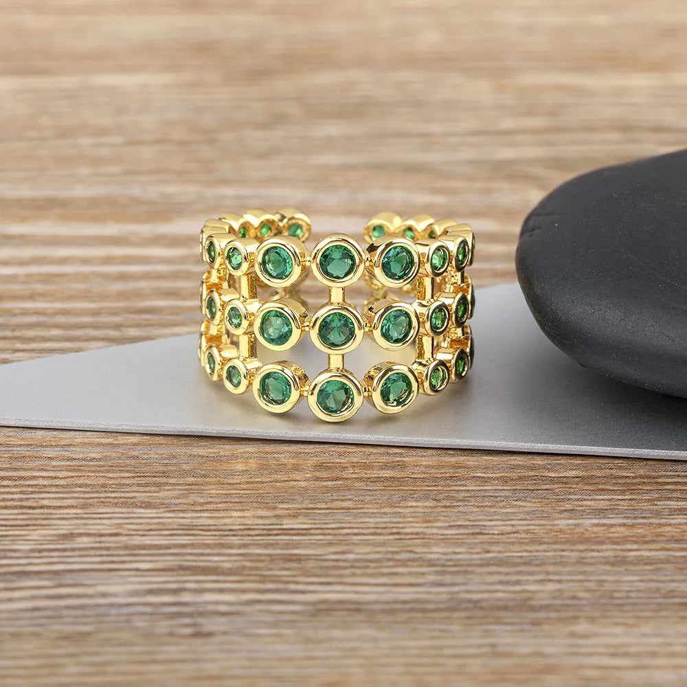 Gold plated ring with three-layer design and green zircon stones on a wide band.