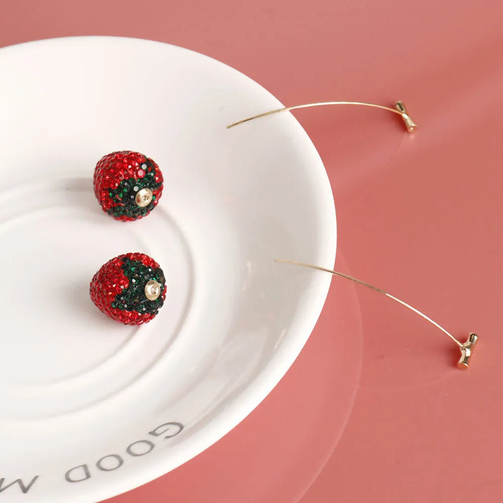 Close-up of geometric spot-drill strawberry stud earrings in red zinc alloy, shown on a plain background.