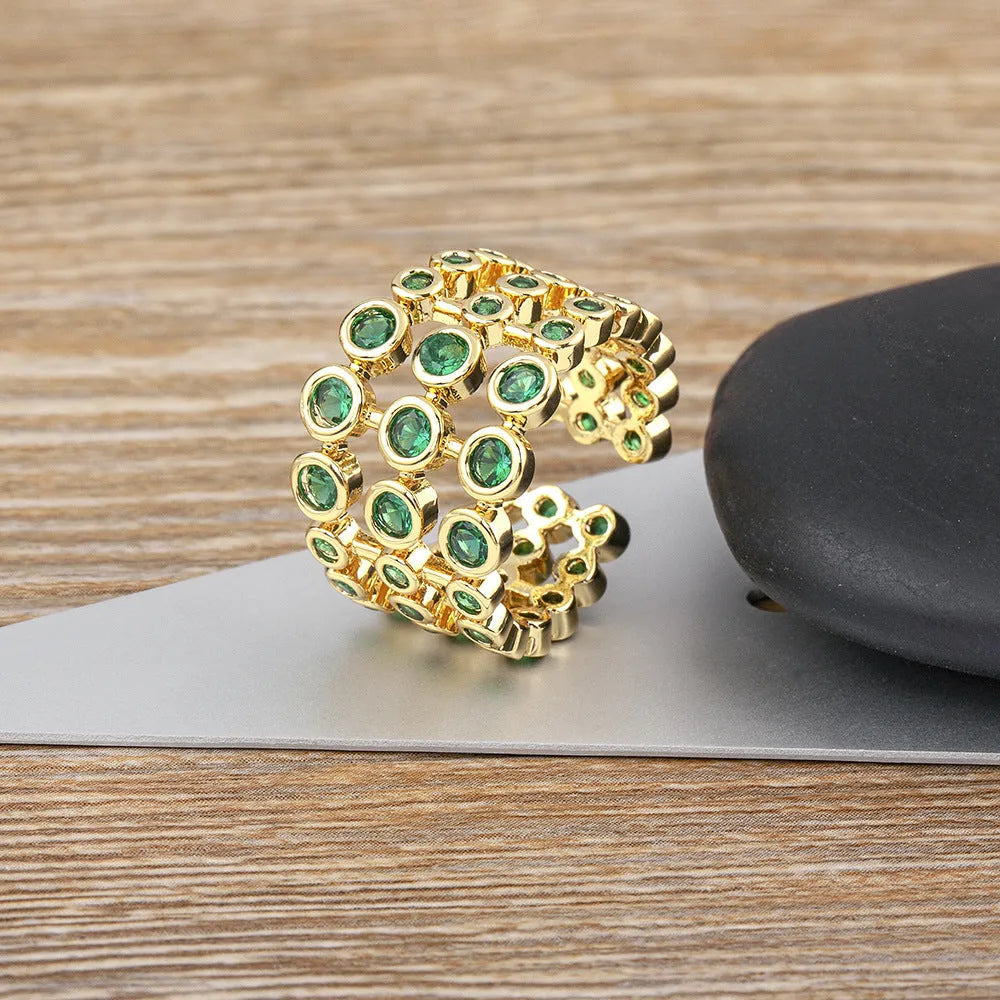 Gold plated ring with three-layer design and green zircon stones on a wide band.