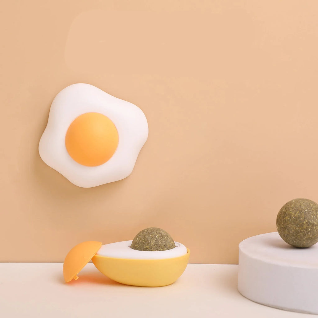 Interactive plush catnip ball toy stuck on a wall, showing Fried Egg and Poached Egg shape options.