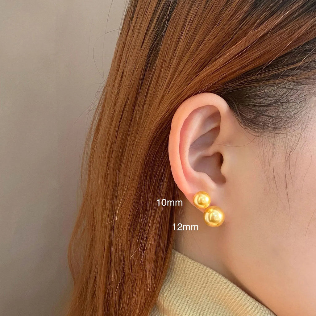 A pair of large pearl stud earrings with a geometric silver setting and an eight-awh star detail on a white background.