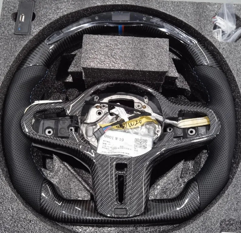 Black carbon fibre steering wheel for BMW with integrated LED display and heating function.