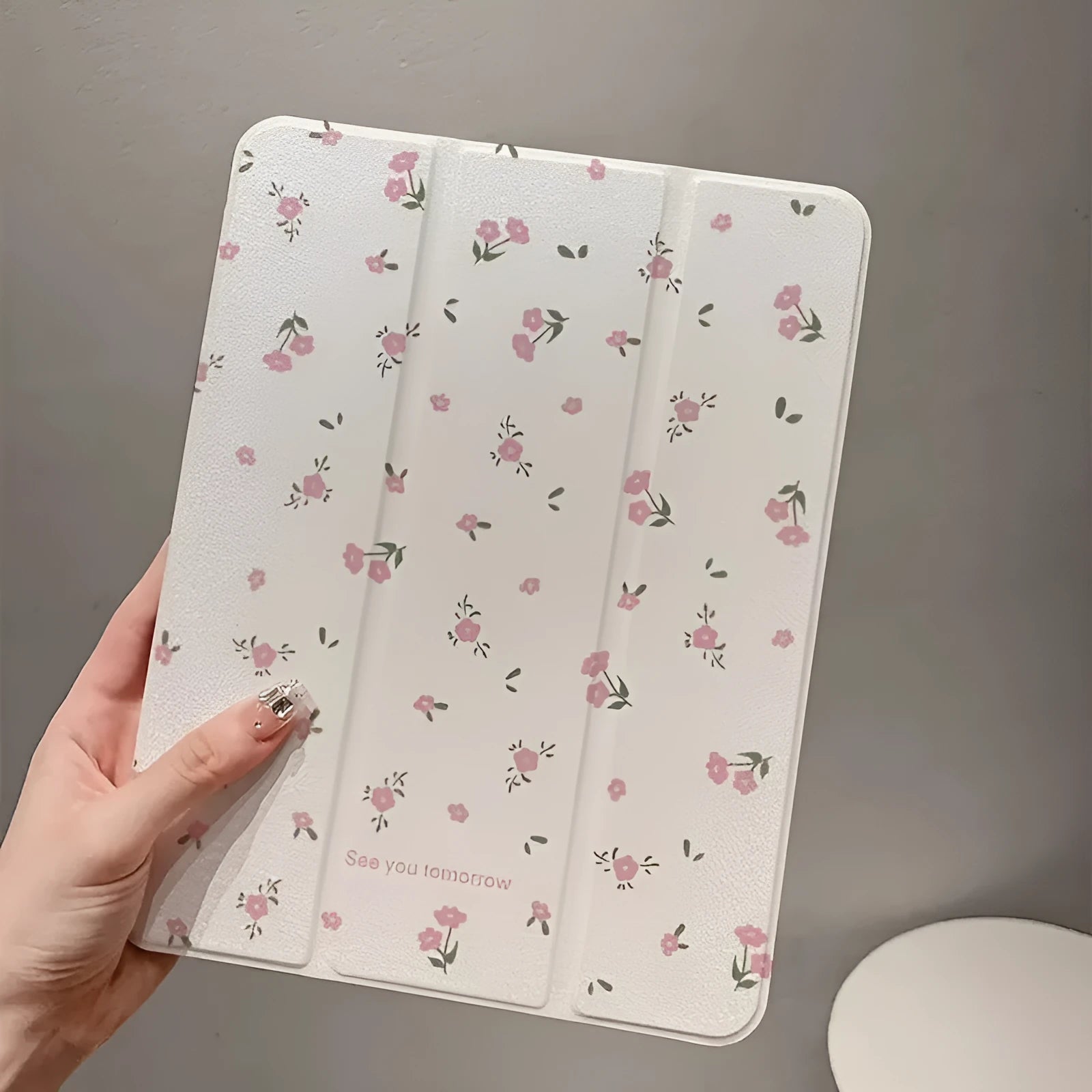Transparent floral tri-fold iPad protective case with built-in stand, shown closed with magnetic clasp.